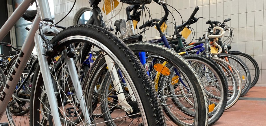 Various ladies' and men's bicycles are lined up in the fire station.