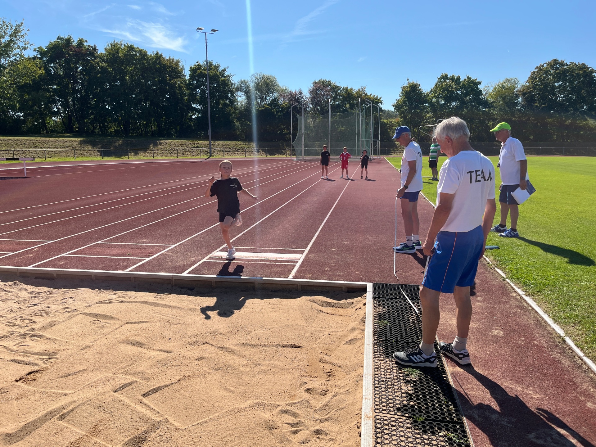 An examiner scrutinises a girl's long jump.