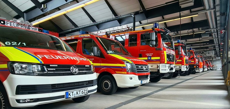 Verschiedene Feuerwehrautos stehen einsatzbereit nebeneinander in der Halle der Feuerwehr der Stadt Kitzingen.