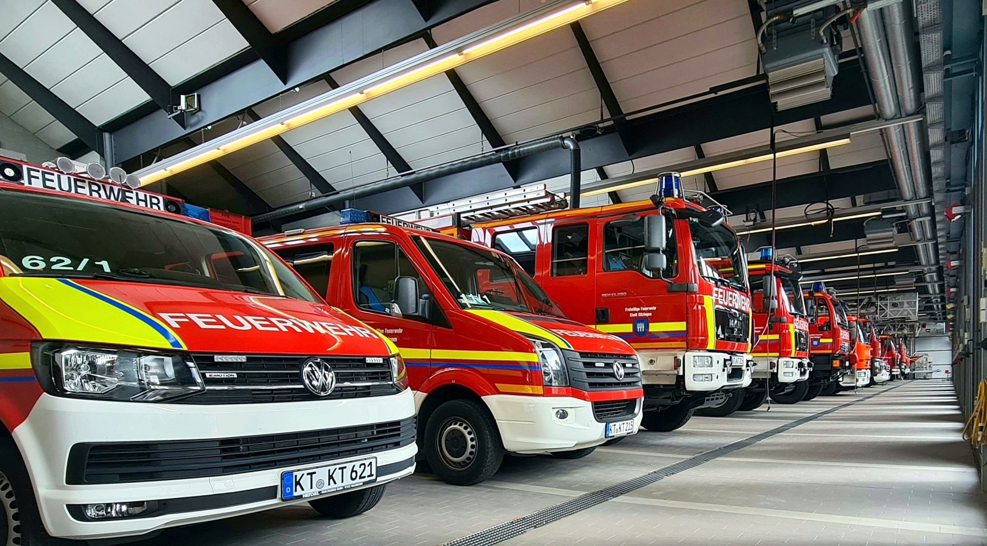 Verschiedene Feuerwehrautos stehen einsatzbereit nebeneinander in der Halle der Feuerwehr der Stadt Kitzingen.