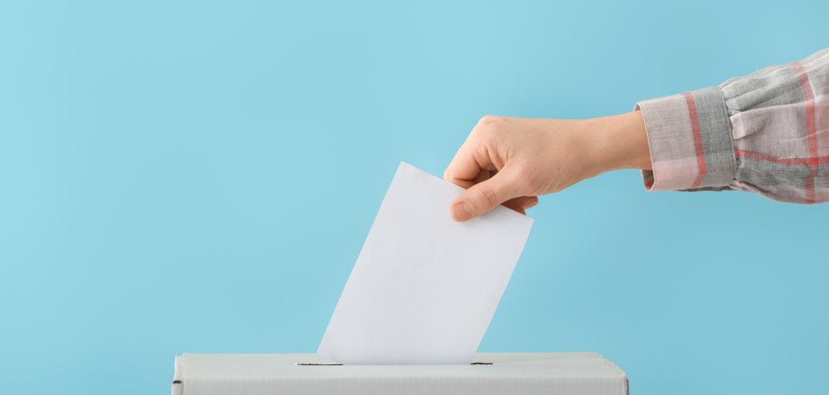 Wahlen Frau, die ihren Stimmzettel in eine Wahlurne wirft.