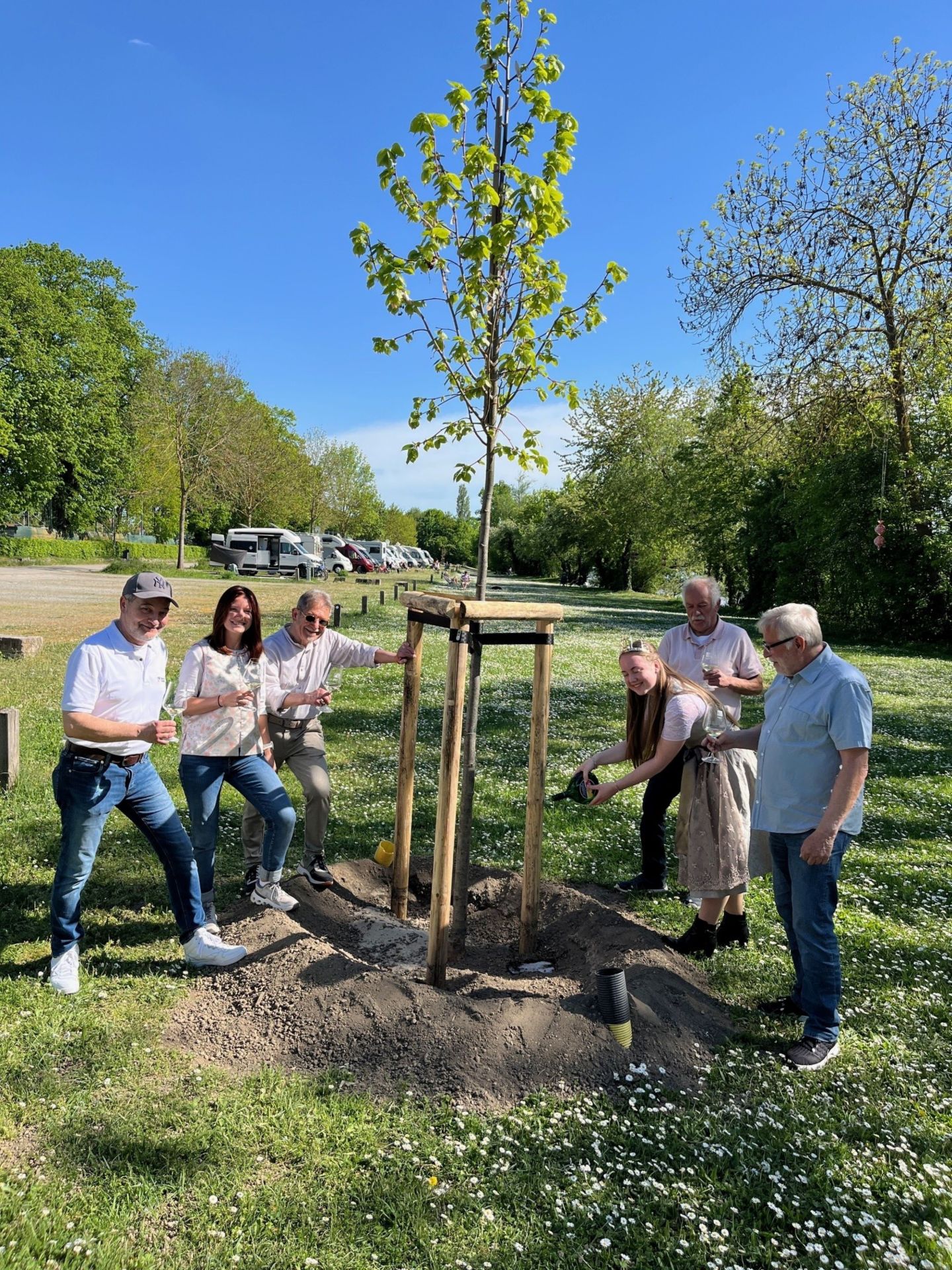 Der neue Baum auf dem Wohnmobilstellplatz wird von Gärtnerkönigin Annika Maurer ordnungsgemäß mit Wein angegossen. Die Tradition beobachten Gästeführer Detlef Hildebrand, TI-Leiterin Christina Richard, Tourismus-Referent Walter Vierrether, Stellplatz-Kontrolleur Dieter Franz und zweiter Bürgermeister Manfred Freitag.