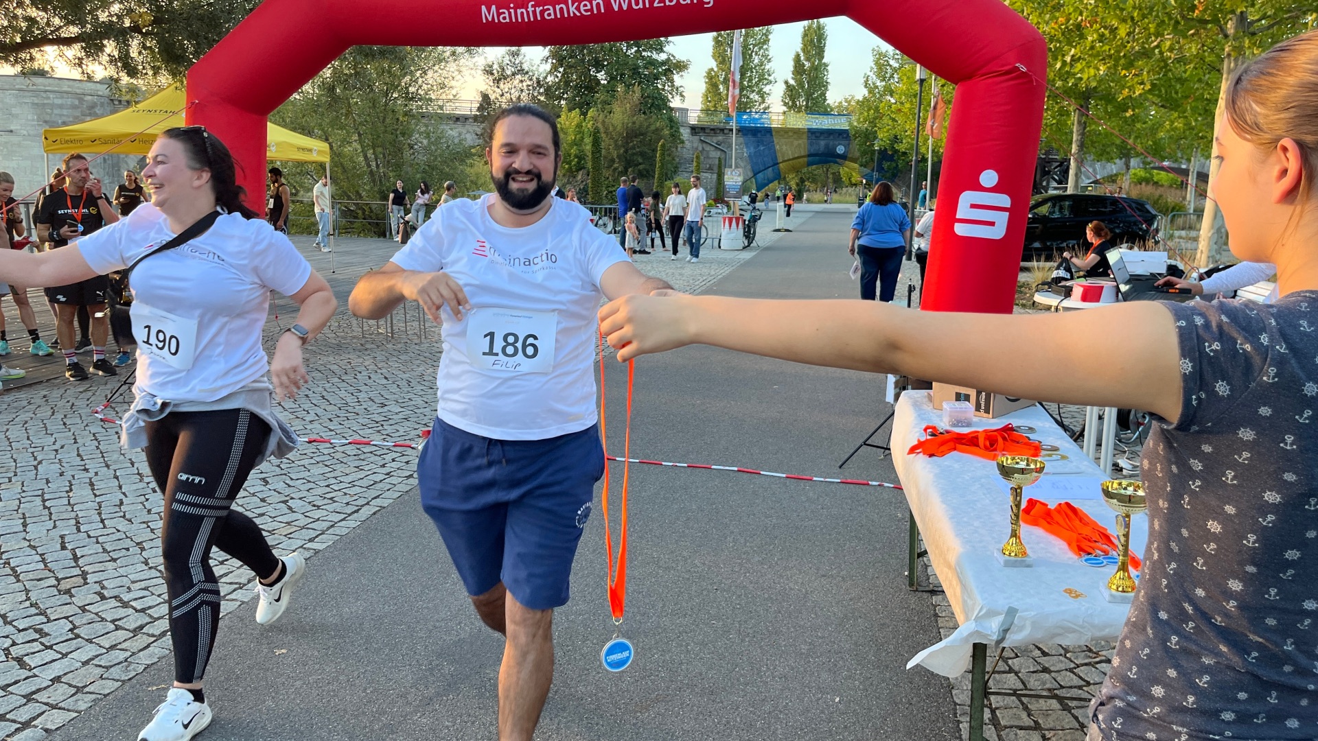 Ein Läufer kommt beim Kitzinger Firmenlauf ins Ziel und erhält eine Medaille.