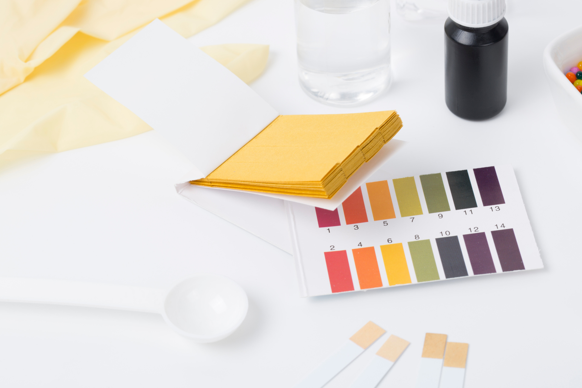 Prüfgeräte für die Sicherheit von Kosmetikinhaltsstoffen, pH-Wert, Wasser-Pulver-Wert, Feuchtigkeitsgrad, pH-Testpapier, Pipette, chemisches Lösungsmittel und Gummihandschuhe vor weißem Hintergrund.