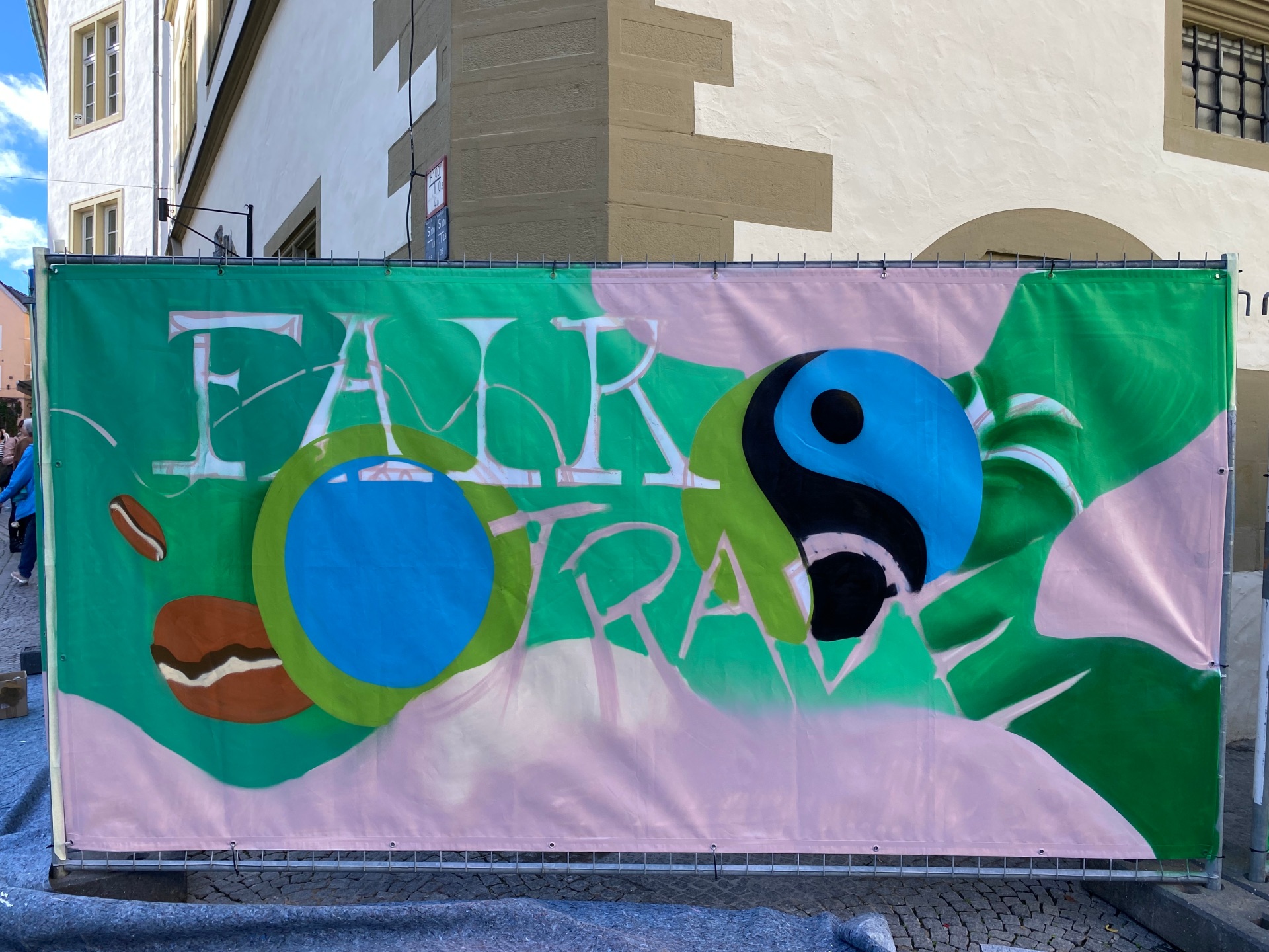 Graffiti zum Fairtrade-Tag 2022 Sprayer Macs besprüht einen Bauzaun zum Fairtrade-Tag 2022.