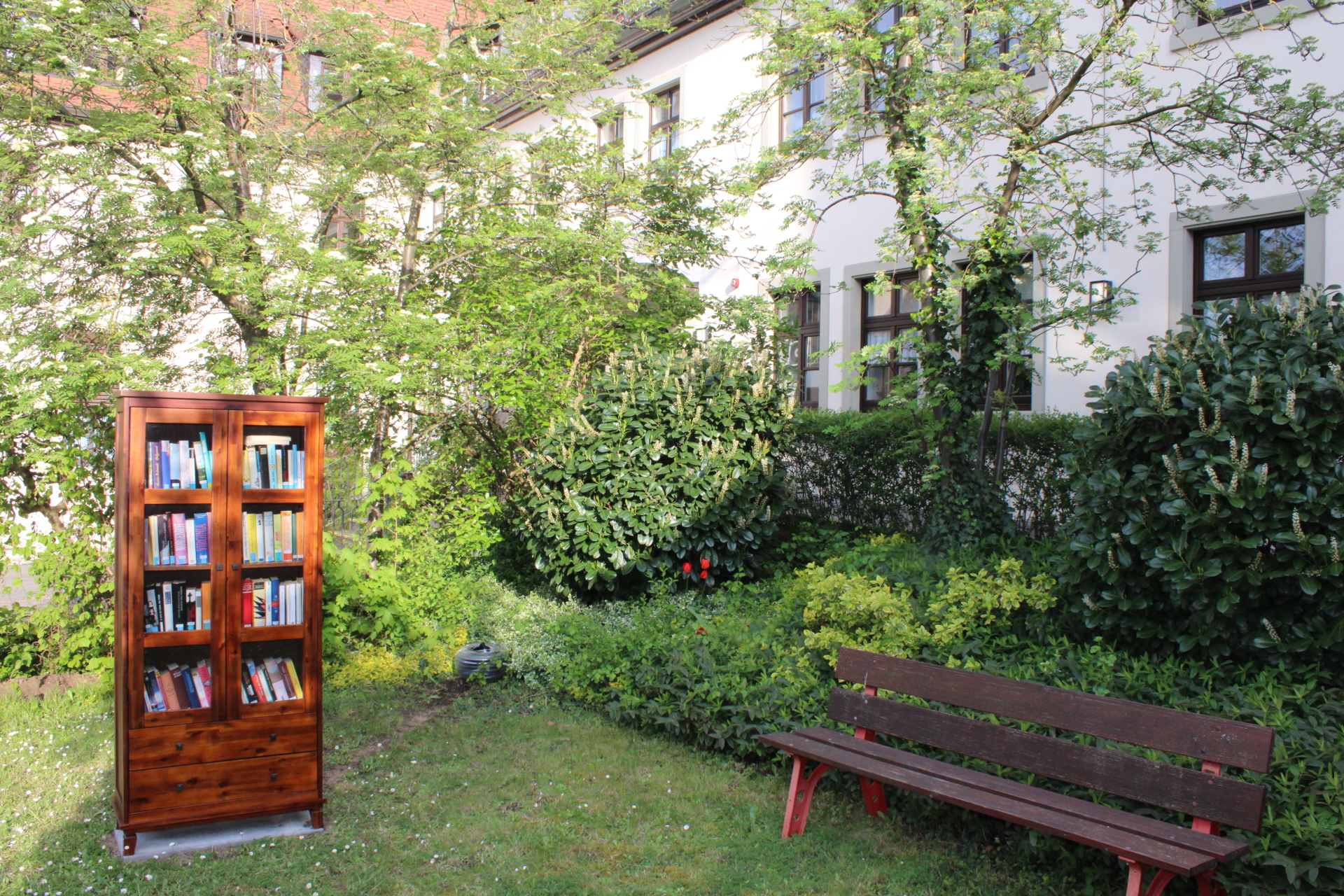 Bücherschrank Mehrgenerationenhaus Der Bücherschrank steht am Mehrgenerationenhaus St. Elisabeth neben einer Bank.