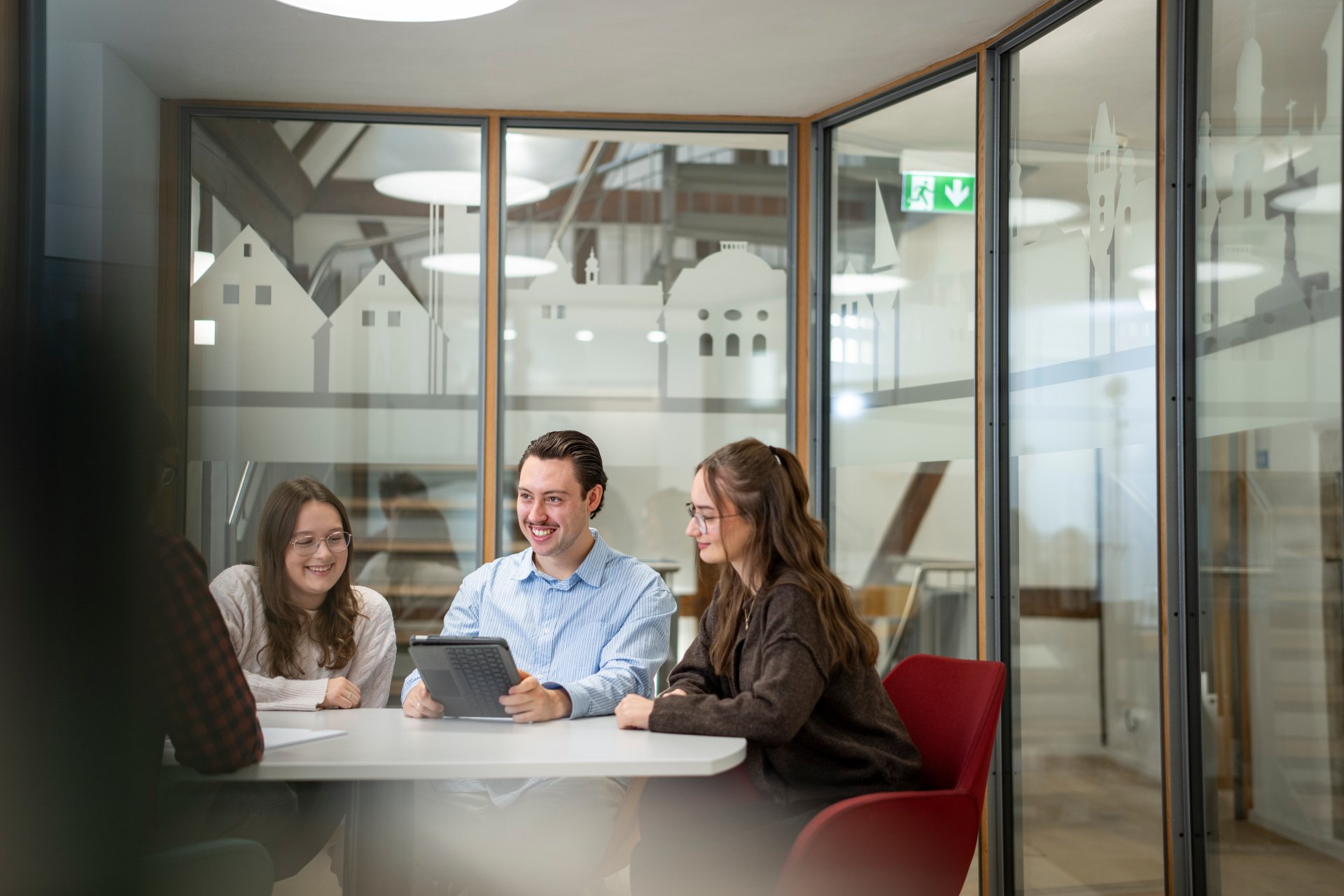 Vier Mitarbeiter sitzen gemeinsam an einem Besprechungstisch und tauschen sich aus.
