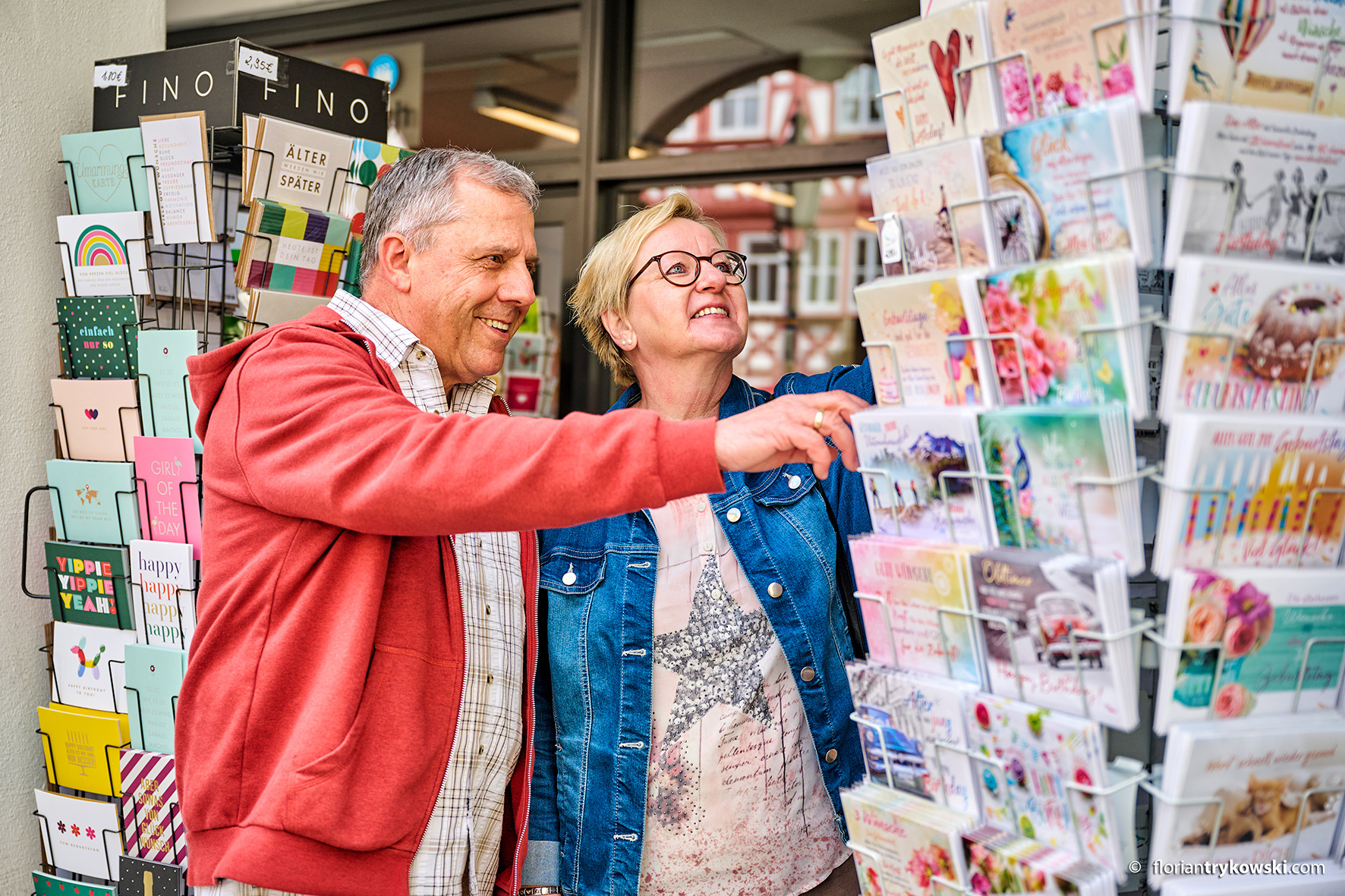 Ein Mann und eine Fraue stehen vor einem Stand mit Grüßkarten