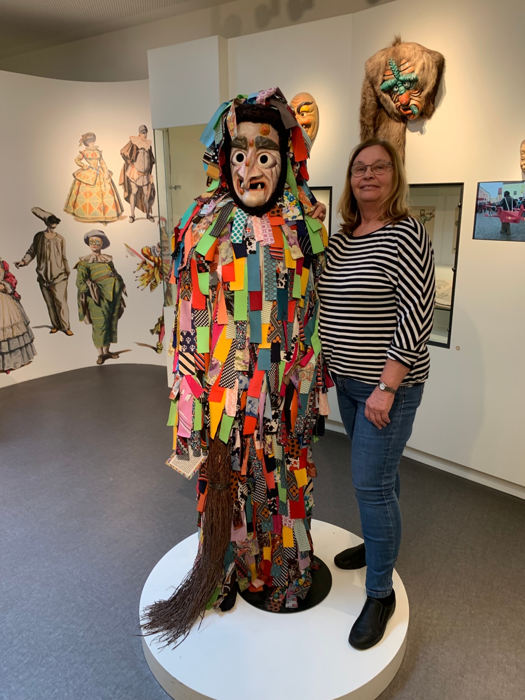 Eine Gästeführerin steht neben einer bunten Karnevalsfigur
