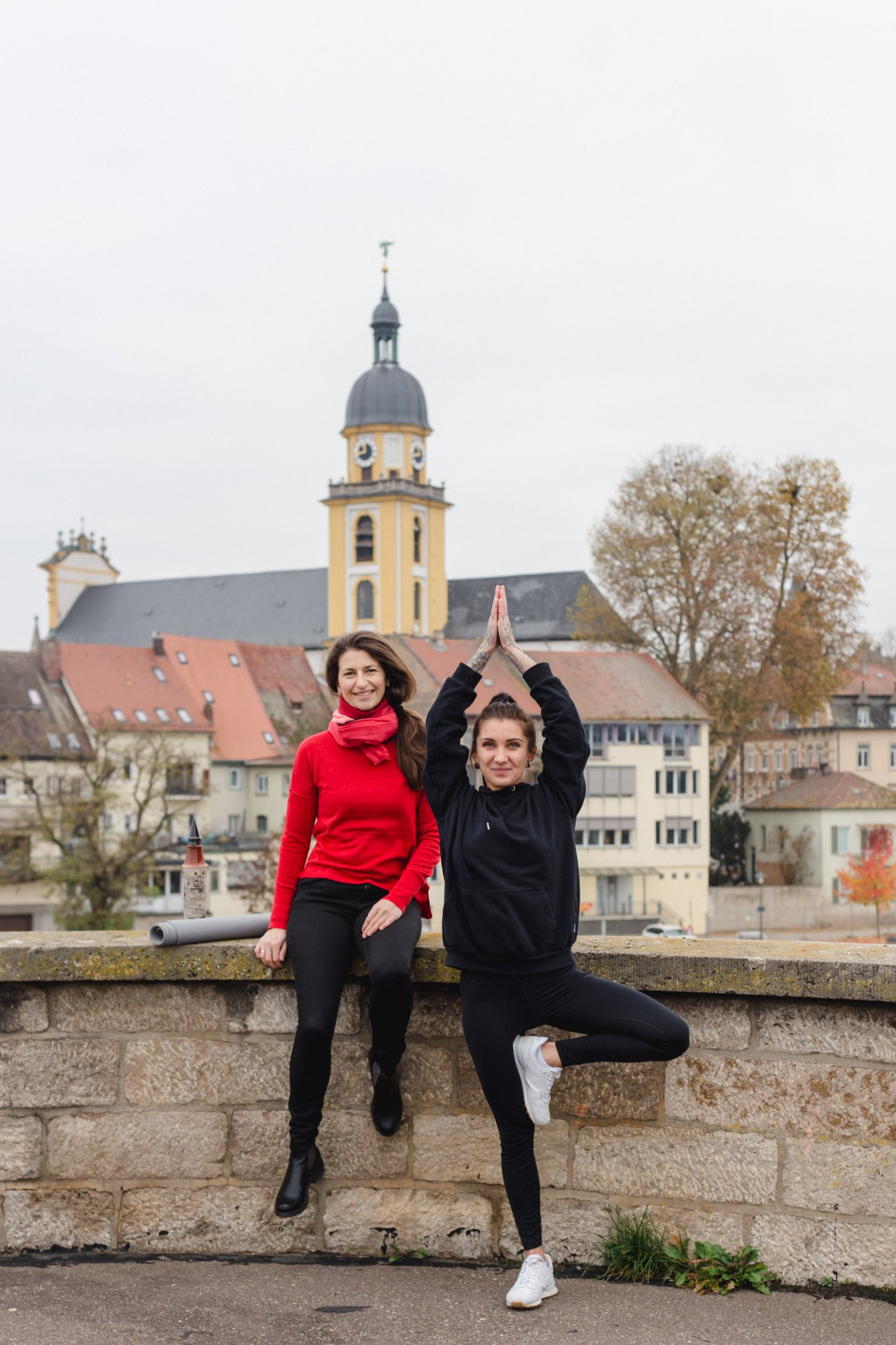 Yogastadtführung Zwei Frauen auf der Alten Mainbrücke, eine davon macht eine Figur aus dem Yoga